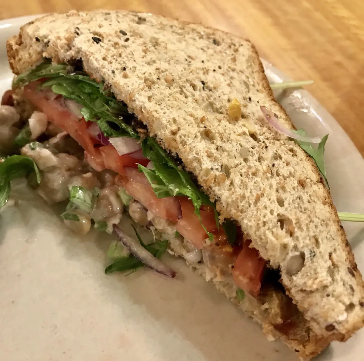 Deli sandwich on wheat bread with lettuce, tomato, and onion.